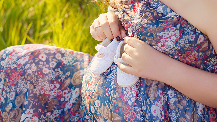Pregnant woman belly holding baby booties. Healthy pregnancy. Newborn baby booties in parents hands. Pregnant woman belly